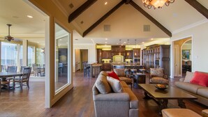 A spacious living area with a large sofa, a dining table, and a kitchen in the background. - Lake Palestine's Best Property for Vacations, Reunions, Events, Get-Aways!!! (Frankston)