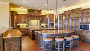 A spacious kitchen with wooden cabinets, a large island with stools, and modern appliances. - Lake Palestine's Best Property for Vacations, Reunions, Events, Get-Aways!!! (Frankston)