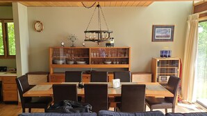 A dining area with a wooden table and chairs, a chandelier, and a bookshelf.