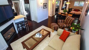 A living room with a sofa, coffee table, and fireplace. There is a dining area with a table and chairs.