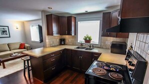 A compact kitchen with dark wood cabinets, a black stove, and a window with a view.