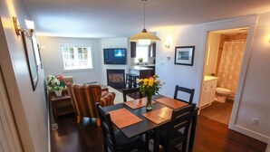 A compact living space with a dining area, a TV, a fireplace, and a visible bathroom.