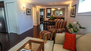 A living room with a sofa, armchairs, a coffee table, and a dining area with chairs and a table.