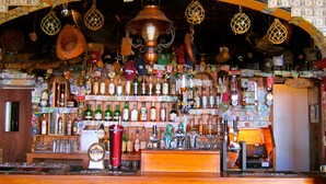A bar with a wooden counter, various bottles, and a cash dispenser. - The Stone House - Wild Atlantic Way (Fanore)