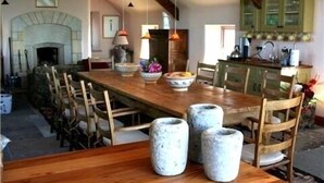 A dining area with a wooden table, chairs, and a fireplace. - The Stone House - Wild Atlantic Way (Fanore)