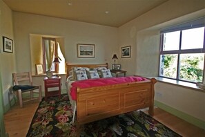Cozy retreat with a comfortable bed, chair, and table near a window.