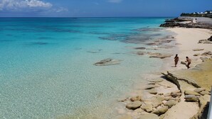 A beach with clear turquoise water, rocky shoreline, and a few people walking. - Luxury Ocean Villa 3 Bed / 3 Bath in Bimini Bay (Bimini)