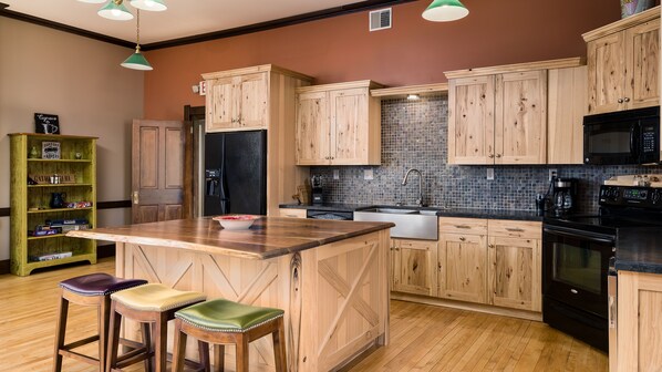 A kitchen with wooden cabinets, a black refrigerator, a sink, and a stove.