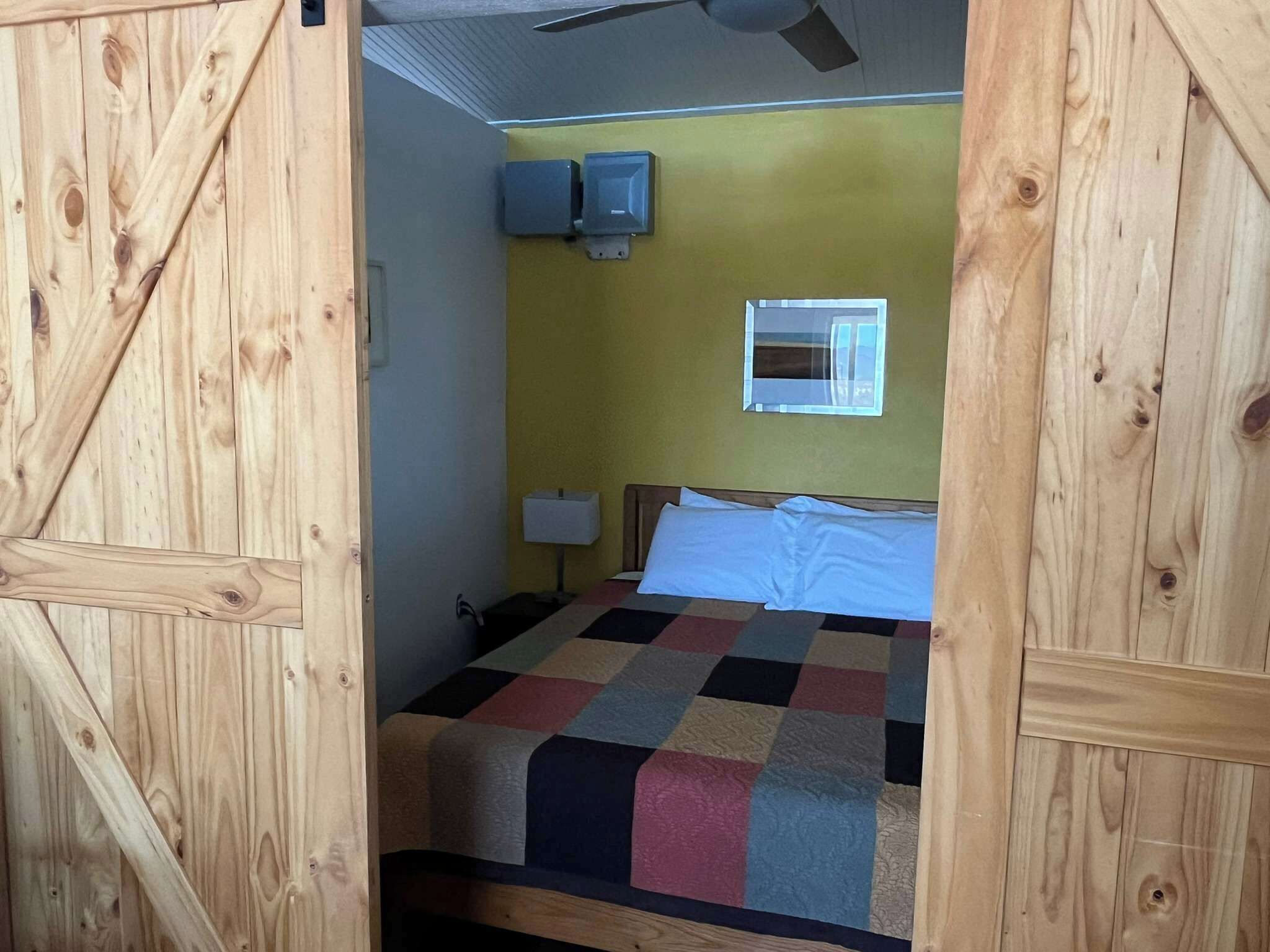 A room with a bed, a ceiling fan, a window, and a wall-mounted air conditioner.