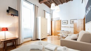 A well-lit room with a wooden floor, a sofa, a desk with a lamp, and a TV on the wall. - SPECIAL OFFER - in the Heart of ancient Rome (Roma)