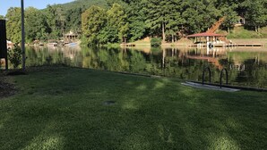 A serene lakeside setting with a grassy area, a dock, and a pavilion.