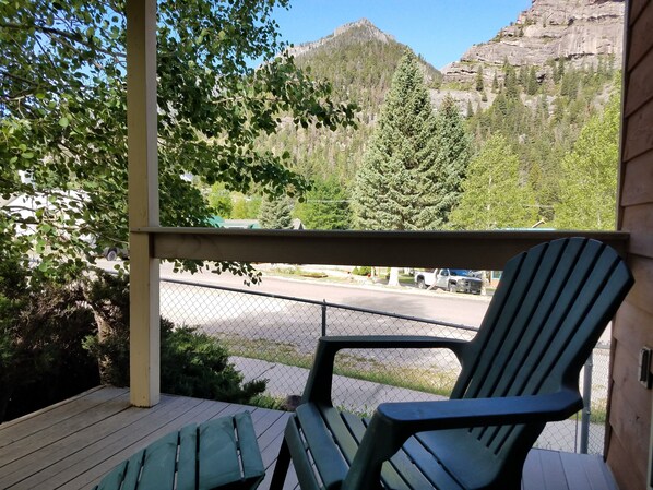 A porch with two green Adirondack chairs, a view of a mountain, and a parking area with vehicles. - Alpine House: 3 Bed, 2 bath - wonderful 'in Ouray' location (Ouray)