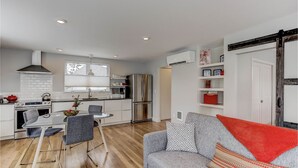 Un espacio habitable compacto con kitchenette, comedor y sala de estar con sofá y mesa de centro.