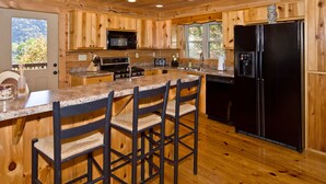 A wooden cabin kitchen with a central island, stainless steel appliances, and a large refrigerator. - Beautiful Mountain Top Retreat Long Range Views, Hot Tub,Ping Pong,Horseshoe pit (Maggie Valley)