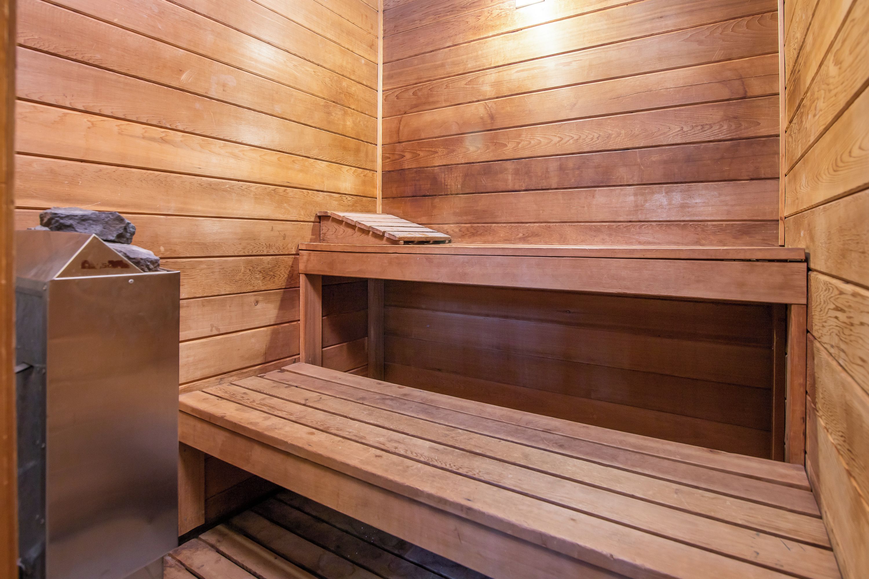A wooden sauna with benches and a small wooden structure on the left.