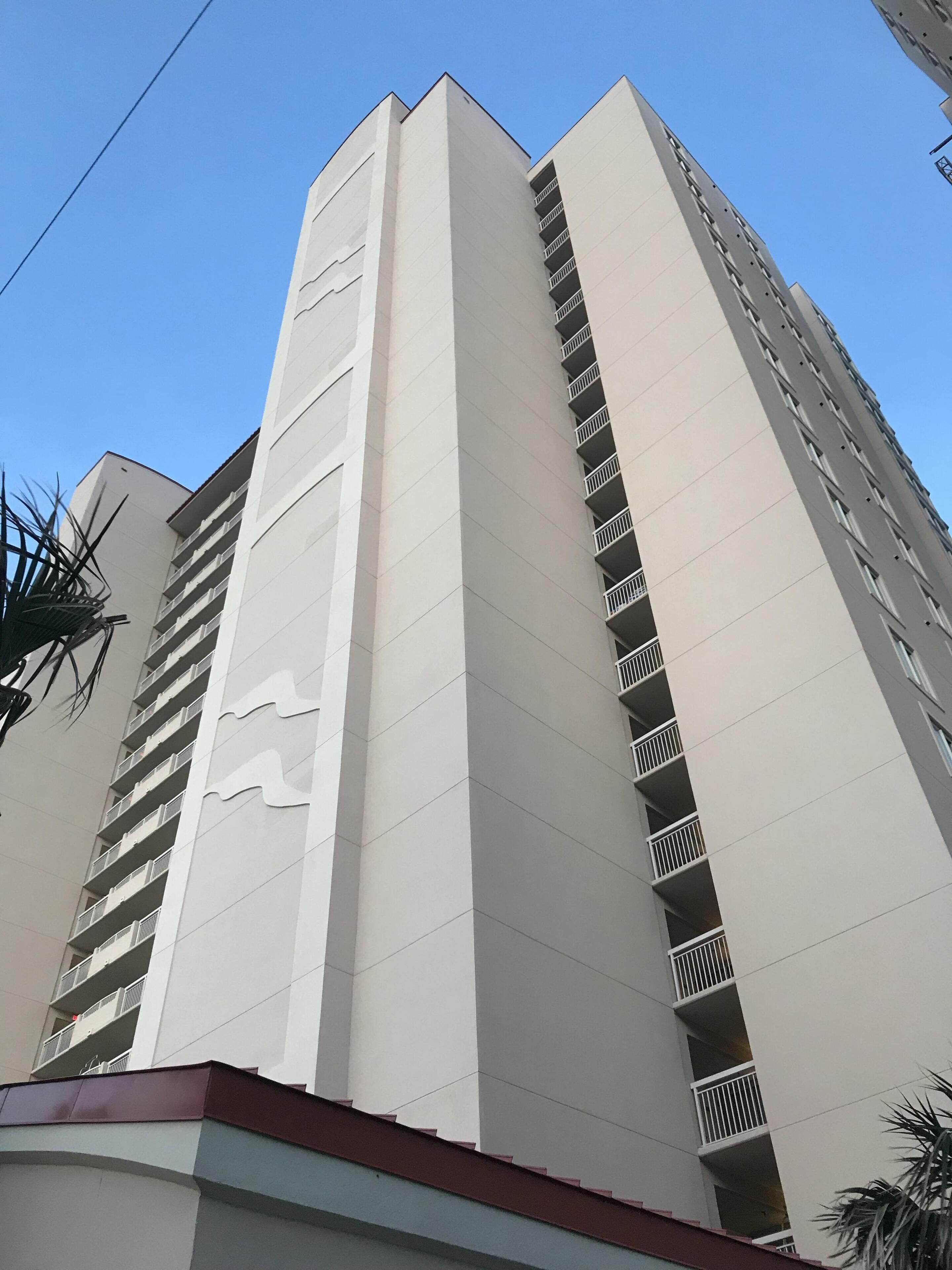 Een hoog, modern gebouw met een witte gevel en meerdere balkons.