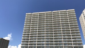Um hotel moderno com vários sacadões, fachada plana e céu azul ao fundo.