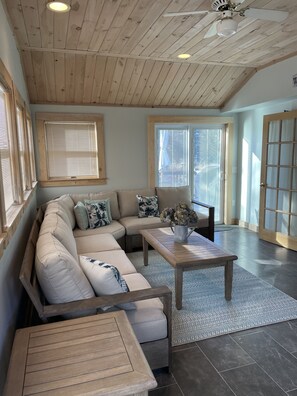 A spacious living room with a wooden ceiling, a large sectional sofa, a coffee table, and a chair. - Ideal Edgartown Village Location-Walk to Town/Bike to Beach (Edgartown)