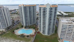 Un hôtel de grande hauteur doté de nombreux balcons, d’une piscine centrale et offrant une vue sur la mer.