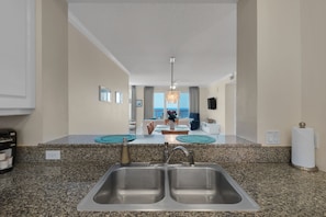 A kitchen with granite countertops, a double sink, and a view of the ocean through large windows. - PENTHOUSE - TOP FLOOR - BEACHFRONT & CHAIRS - POOL - BALCONY - GYM-NEW ELEVATORS (Navarre)