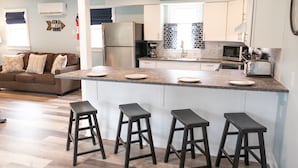 A modern kitchen with a central island, bar stools, and a 'Happy Hour' sign.