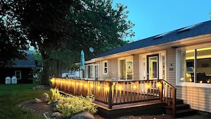 A house with a wooden deck, a porch with steps, and a window with a decorative design.