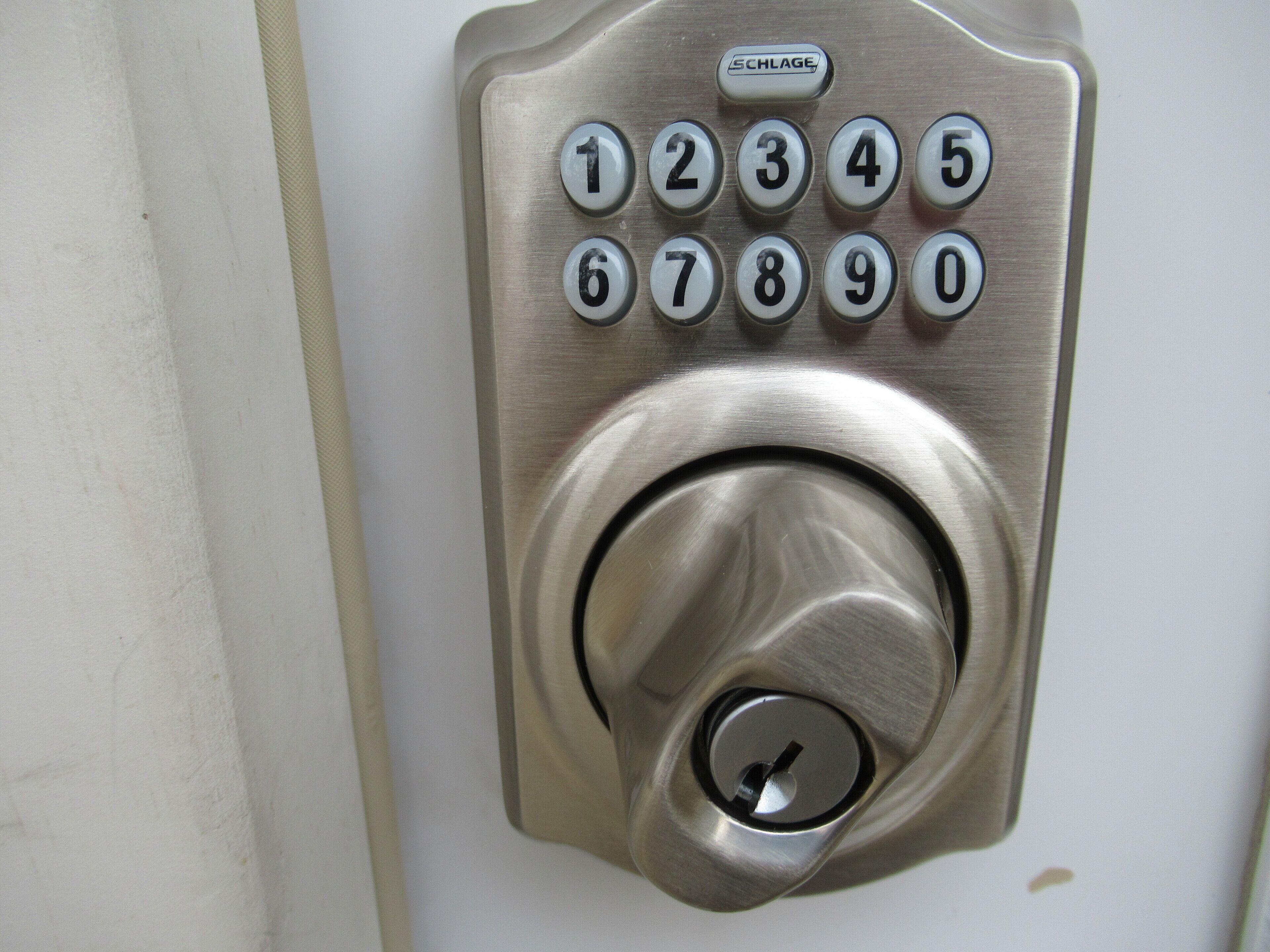 A metallic keypad lock with numbers 0-9 and a central keyhole.