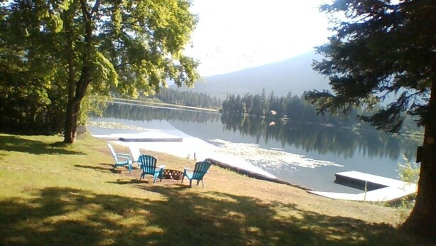 Vista de un lago con muelle, sillas y una mesa pequeña.