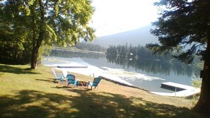 Vista de un lago con muelle, sillas y una mesa pequeña.