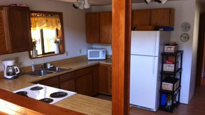 Una cocina con armarios de madera, una estufa blanca, un fregadero, un microondas y un refrigerador.