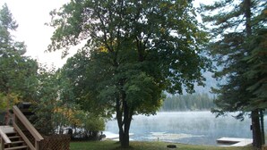 Una propiedad frente al lago con muelle de madera, un árbol y vistas al lago.