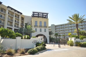 A multi-story hotel with balconies, a central archway, and a gated entrance. - Bella Riva 202 • Luxury 4 BR, 3rd Floor, Beachfront, Pool, Hot Tub, Free Beach Service (Fort Walton Beach)