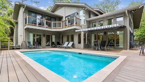 A two-story house with a swimming pool, outdoor seating, and a covered patio area.