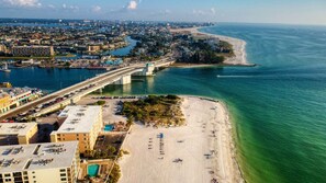 An aerial view of a coastal city with a prominent bridge, a beach, and a marina.