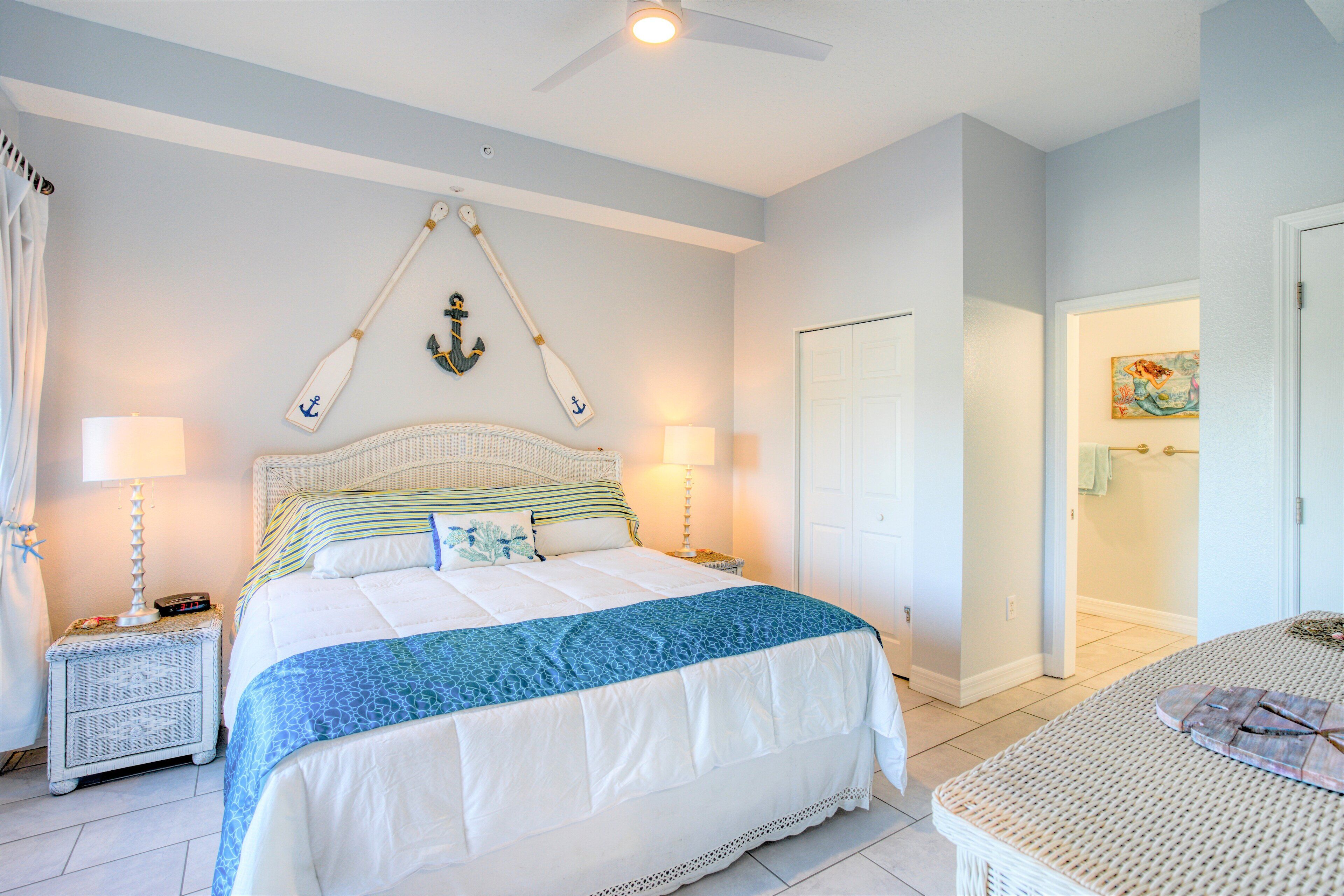 A bedroom with a bed, two nightstands, a ceiling fan, and a door leading to a bathroom.