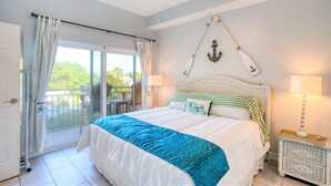 A bedroom with a large bed, a balcony with curtains, and a wall-mounted anchor decoration.