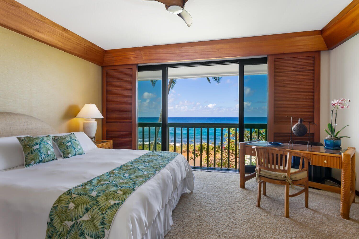 A hotel room with a bed, a desk, and a view of the ocean.