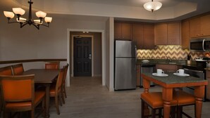 Una cocina moderna con armarios de madera, un refrigerador de acero inoxidable, un microondas y un comedor con mesa y sillas.
