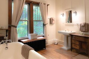 Ein Badezimmer mit einer Badewanne, einem Waschbecken und einem Fenster mit Vorhängen.