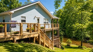 A light blue house with a wooden deck and a small porch.