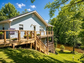 A light blue house with a wooden deck and a small porch.