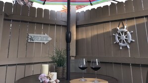 A round table with two wine glasses and a candle, under a colorful striped umbrella. - A good morning of sunshine begins with you being here, so why wait to come down? (Panama City Beach)