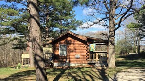A rustic cabin with a wooden exterior, a small porch, and a visible window.