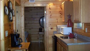 A wooden cabin interior with a kitchen area, including a coffee maker, microwave, and sink.