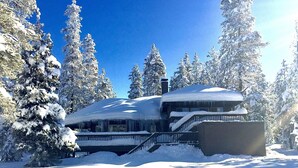 A snow-covered lodge with a prominent chimney, surrounded by evergreen trees. - 5-bedroom vacation home steps to the Deschutes River (Sunriver)