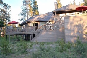 Enjoy the serene surroundings from the covered outdoor area and wooden deck with a staircase leading to the upper level.