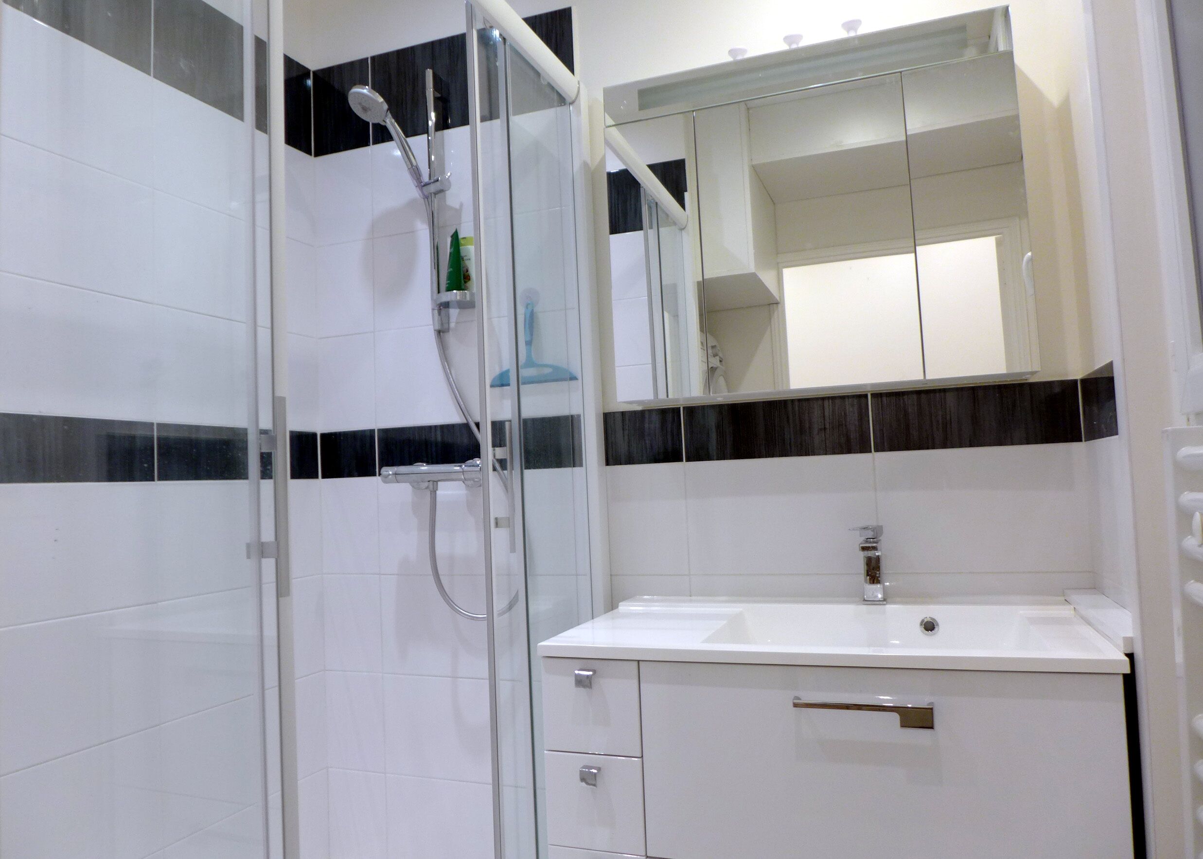 Un baño moderno con cabina de ducha de vidrio, un lavabo blanco y un espejo sobre él.