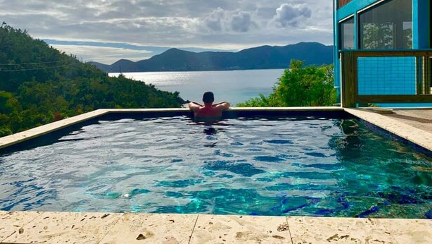 A person relaxing in a pool with a scenic view of mountains and a lake. - Gorgeous View, Beach Access, Swimming Pool, Kayak, Quiet Privacy - the East End (St. John)
