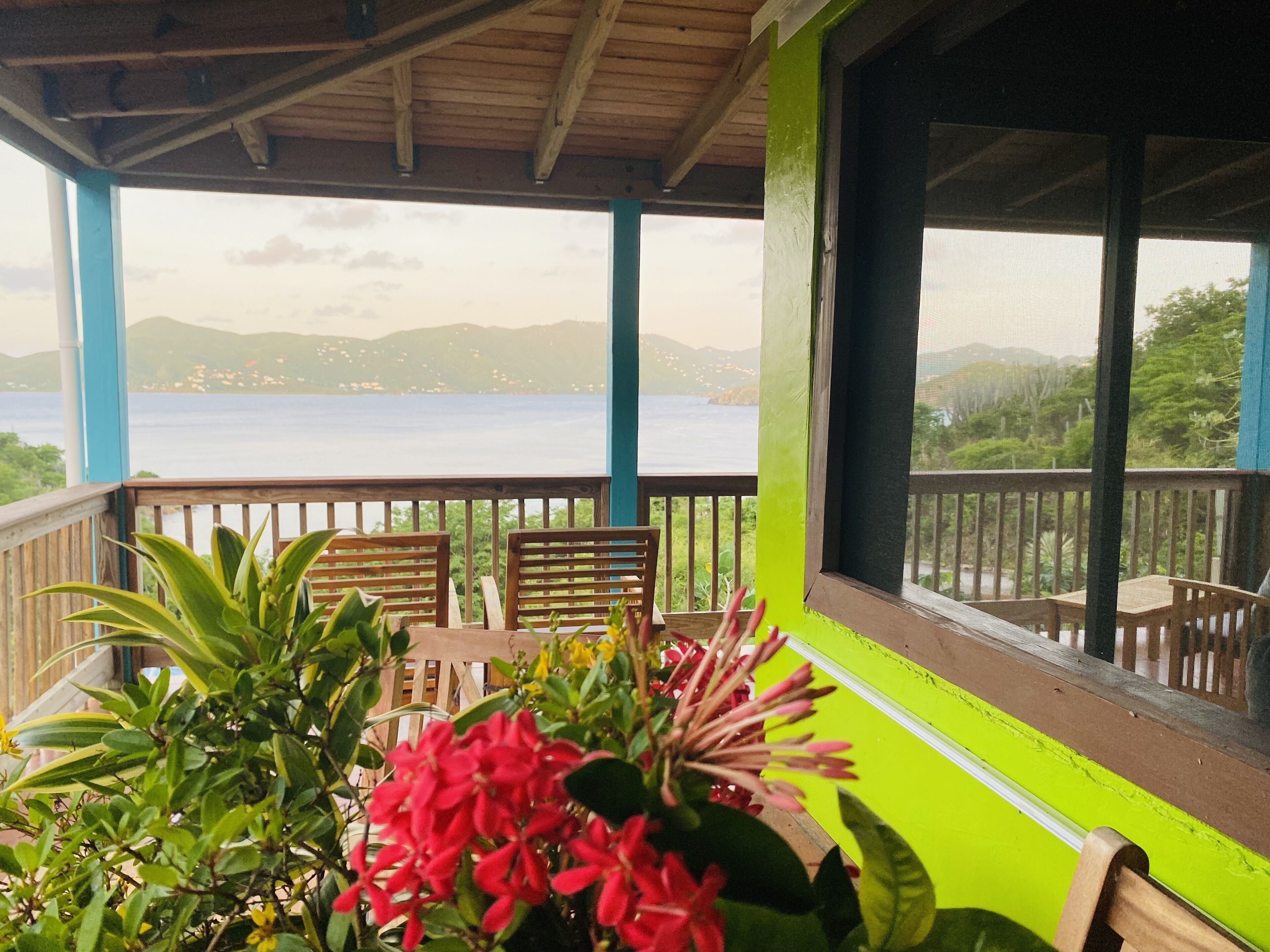 Un espacio de estar al aire libre techado con mobiliario de madera y vista al mar.