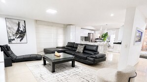 A modern living room with a sectional sofa, a glass coffee table, and a patterned rug.